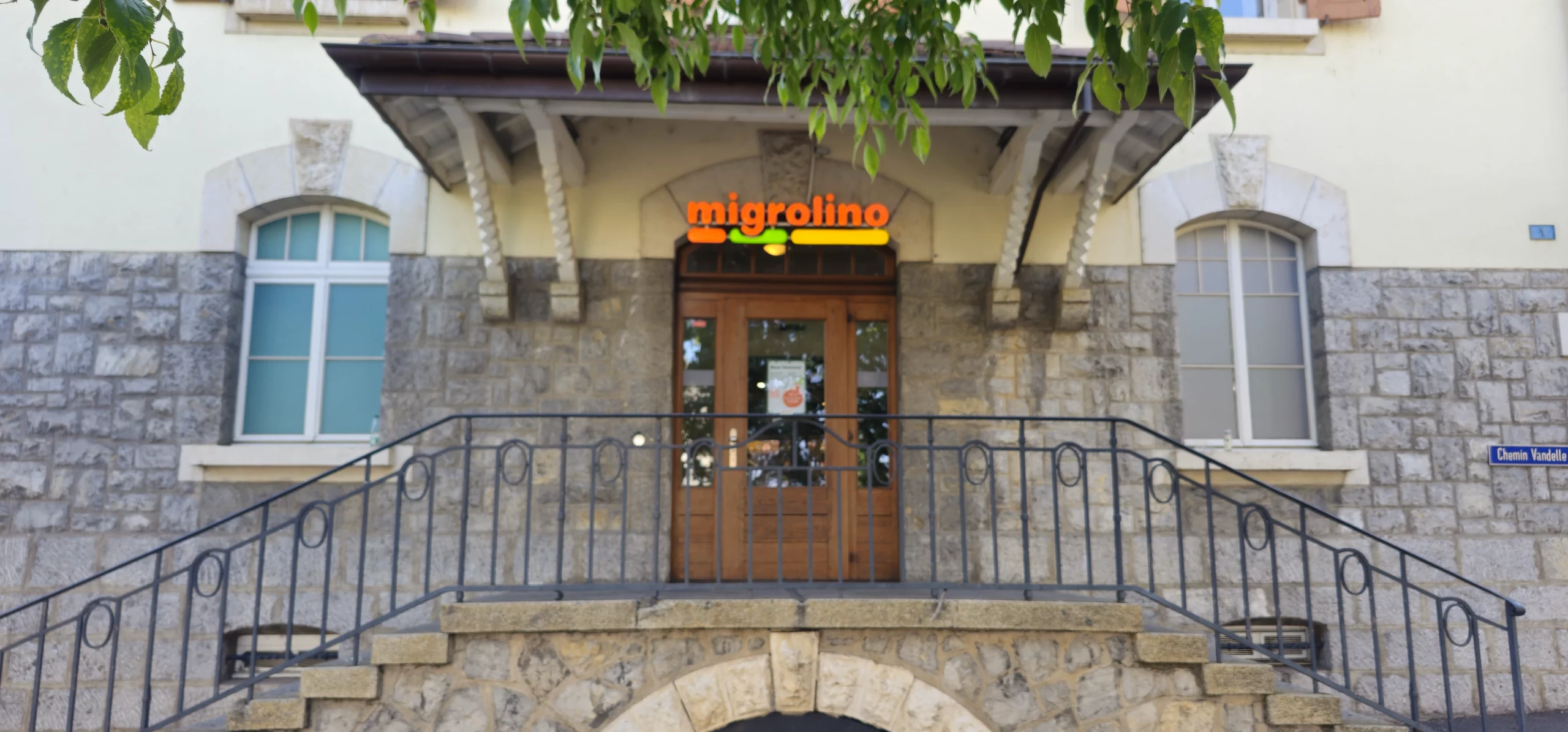 Façade du bâtiment de la gare de Versoix, avec l’enseigne Migrolino au-dessus de la porte d’entrée