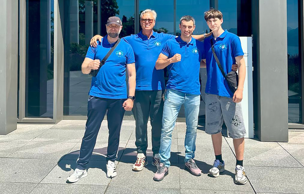 Quatre hommes en polo bleu du Boxing Club Versoix posent devant le Musée Olympique de Lausanne